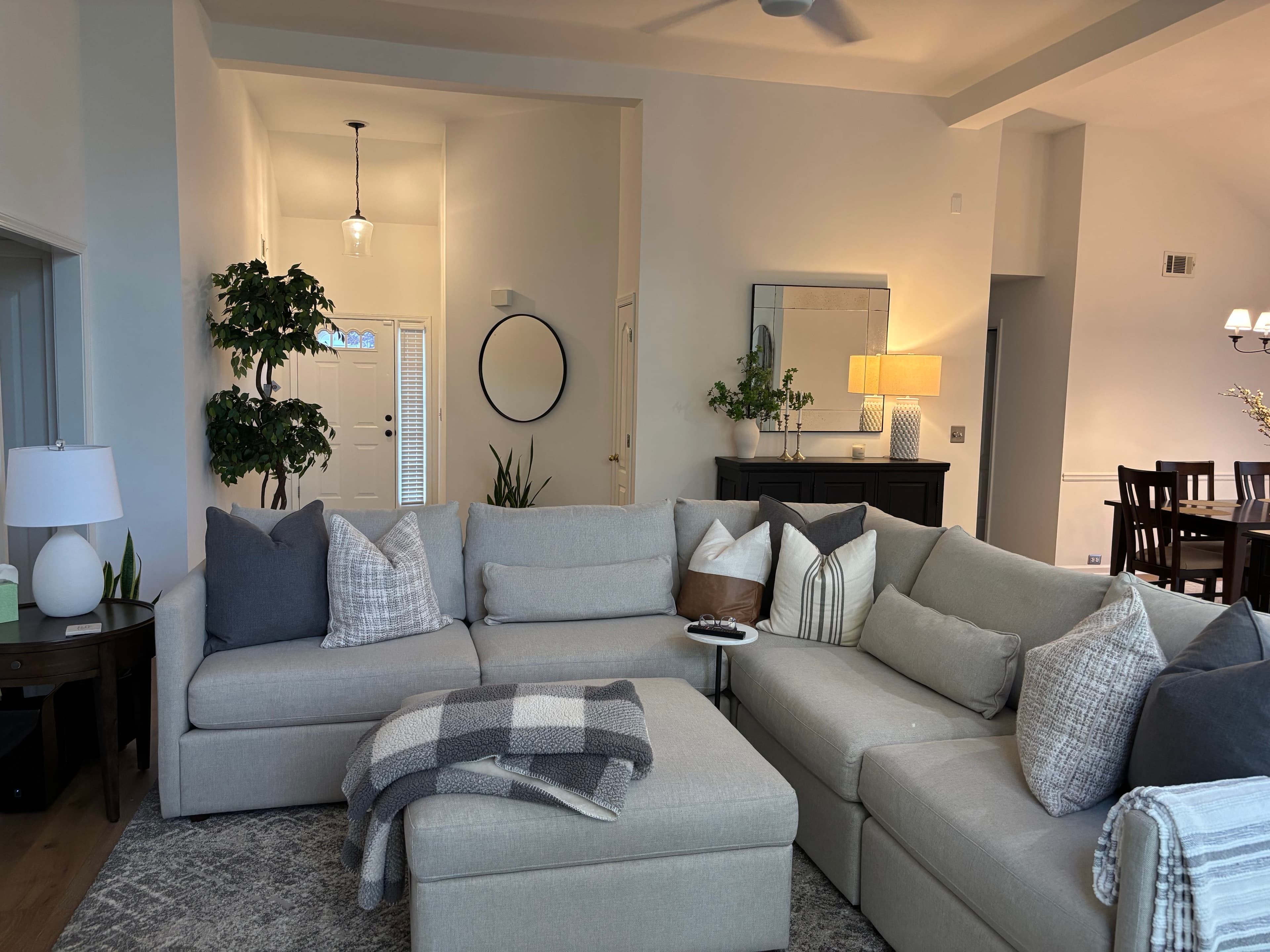 Whole-home remodel with an open-concept living room, neutral sectional seating, a styled entry niche, and dark trim accents.